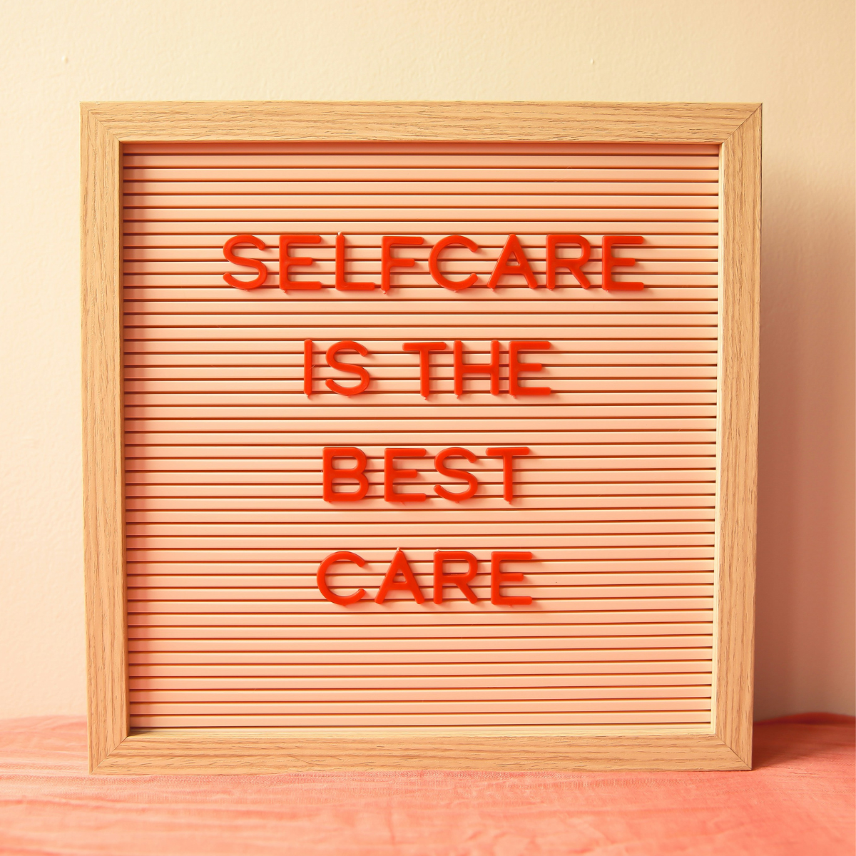 Framed square message board with “selfcare is the best care” written in red capital letters.